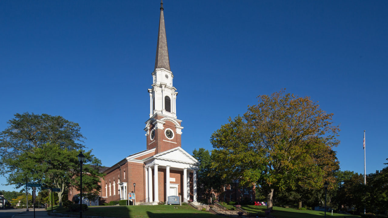 brick church wit white columns and steeple on top of hill in Wellesley, MA
