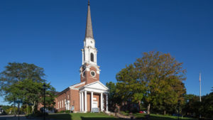 brick church wit white columns and steeple on top of hill in Wellesley, MA