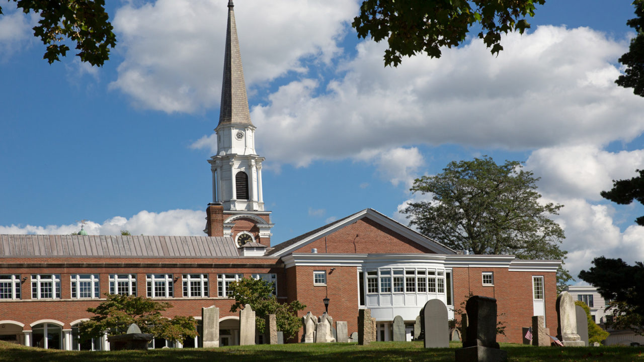 ground level view of headstones, brick church with white steeple beyond, minutes from The Bristol luxury condos.