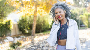 Smiling Black woman with gray hair walking in beautiful park