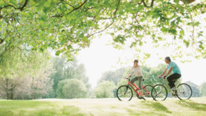 Two people on bikes on bright day in early bright green summer