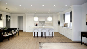 All white kitchen cabinetry, counter with 2 white overhead ball lamps in open floorplan. Dining table to left. Traditional finish package at The Bristol